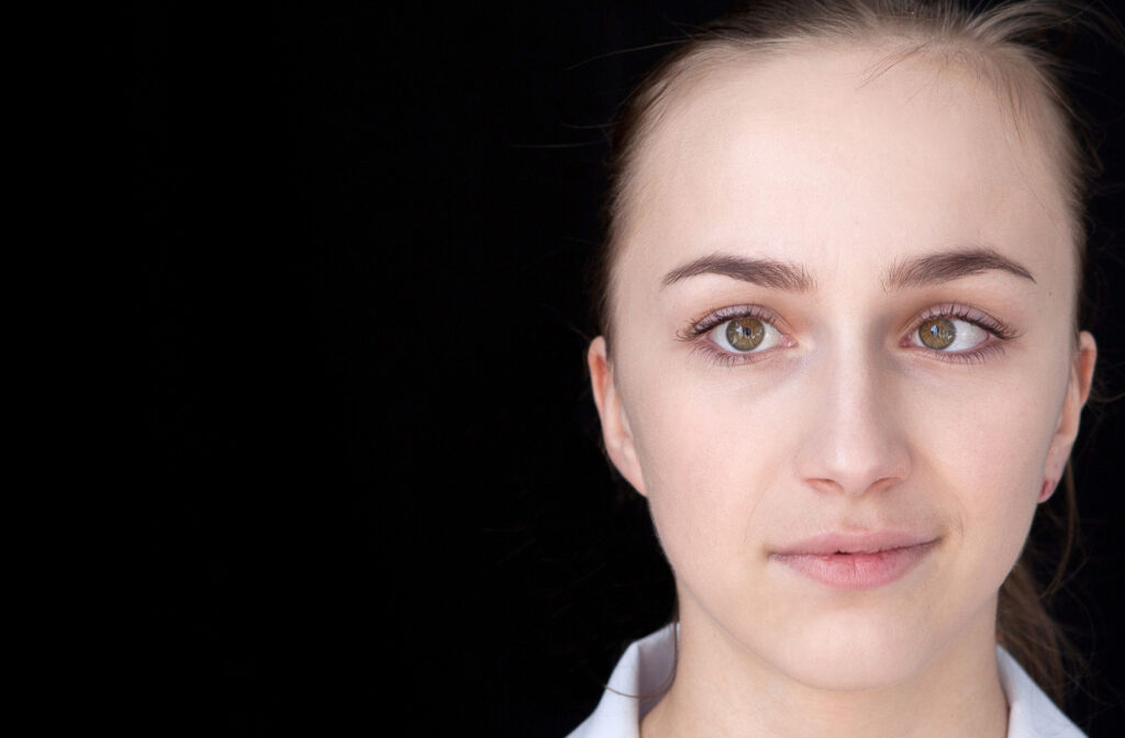 A young woman with a cross eye against a black background.